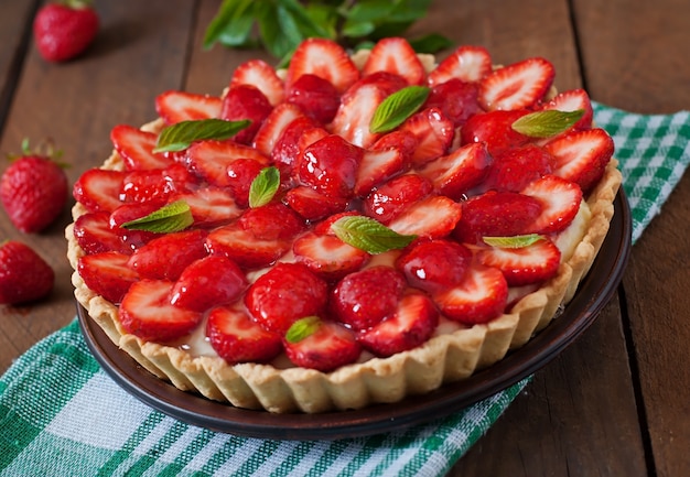 Tarta de fresas y crema batida decorada con hojas de menta.