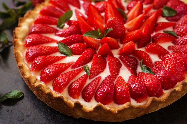 Tarta de fresas y crema batida decorada con hojas de menta.