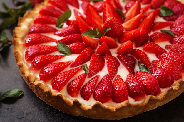 Tarta de fresas y crema batida decorada con hojas de menta.