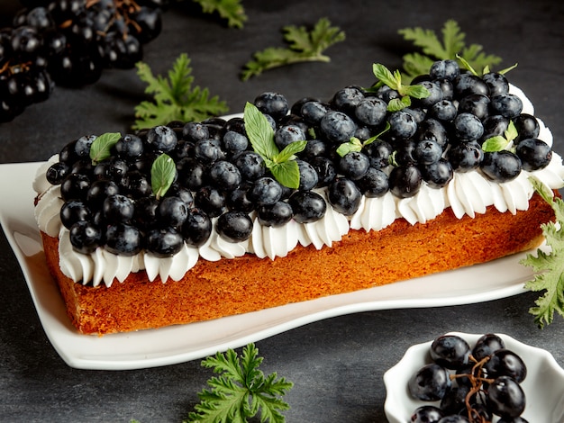 Tarta larga decorada con crema blanca y arándanos