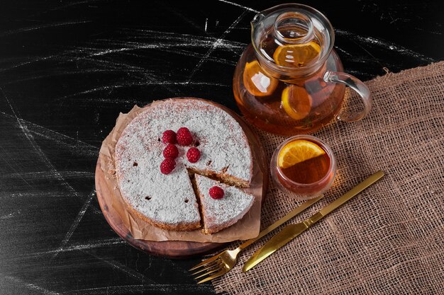 Tarta de limón y bebida en bandeja de madera.