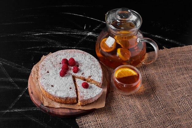 Tarta de limón con frutos rojos en bandeja de madera.