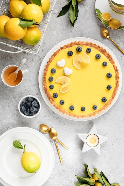 Tarta de limón tradicional francesa con arándanos sobre un fondo de piedra blanca Vertical