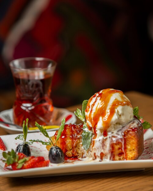 tarta de manzana cubierta con una bola de helado adornada con uva y fresa