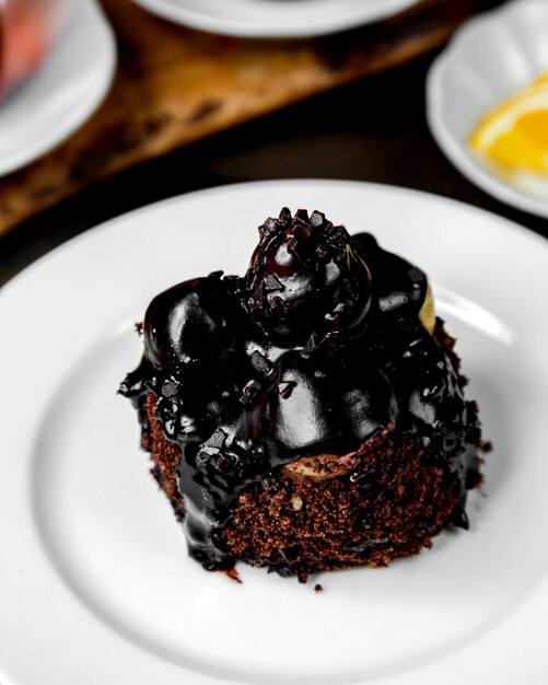 Tarta marrón con cerezas y jarabe de chocolate encima