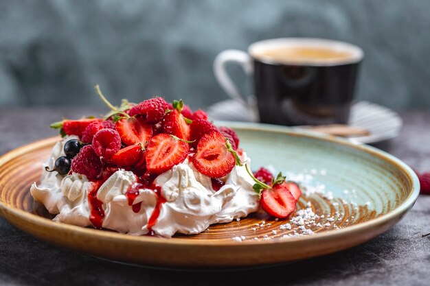 Tarta de merengue decorada con frambuesa, grosella negra y jarabe