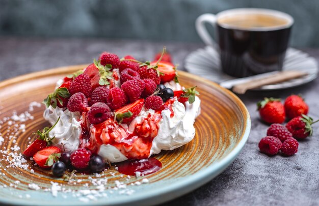 Tarta de merengue decorada con frambuesa, grosella negra y jarabe