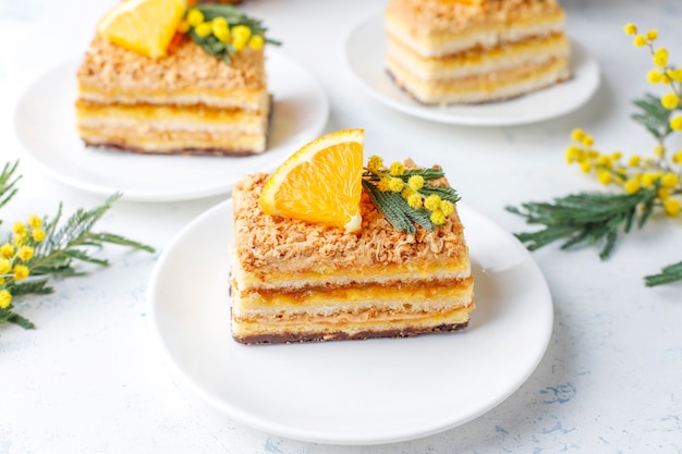 Tarta de naranja decorada con rodajas de naranja fresca y flores de mimosa en luz