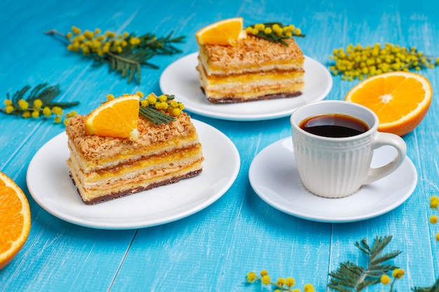 Tarta de naranja decorada con rodajas de naranja fresca y flores de mimosa en luz