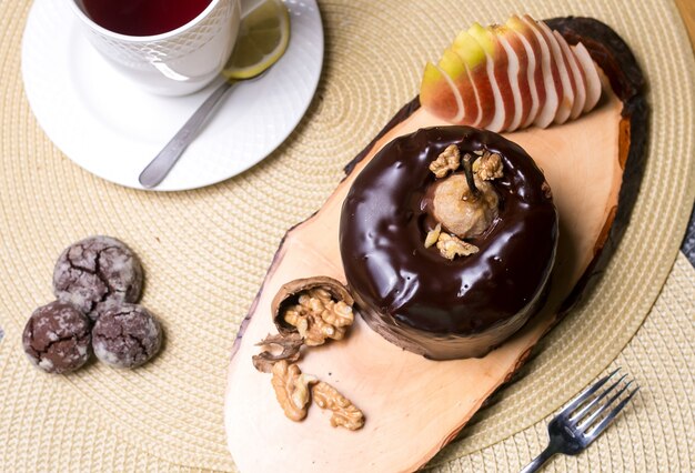 Tarta de pera en la tabla de madera con nueces chocolate y frutas frescas vista superior