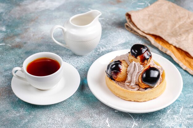 Tarta con profiteroles encima con nata montada.