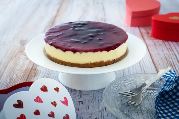 Tarta de queso con arándanos decorada con corazones dulces en una mesa de madera