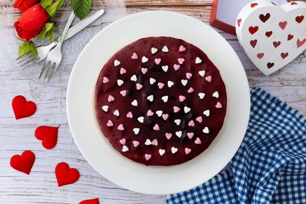 Tarta de queso con arándanos decorada con corazones dulces en una mesa de madera