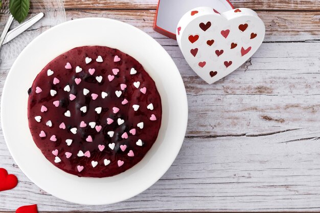 Tarta de queso con arándanos decorada con corazones dulces en una mesa de madera