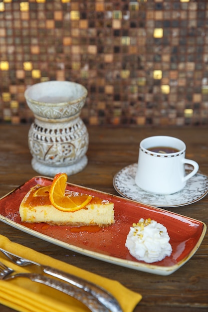 Foto gratuita tarta de queso con crema de naranja, servida con té