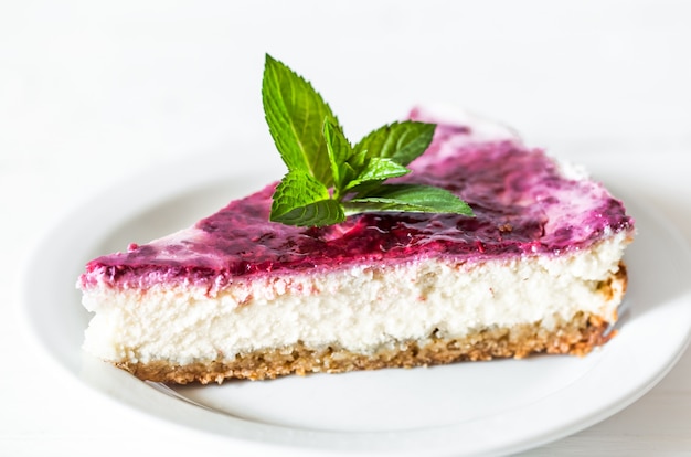 Tarta de queso de frambuesa con hojas de menta sobre fondo blanco, concepto, confitería