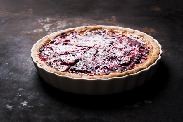 Tarta de queso con frambuesa en una mesa de madera oscura