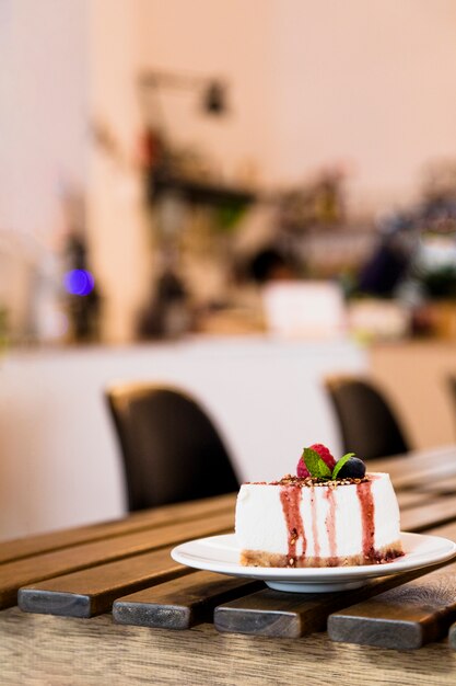 Tarta de queso con fresas y menta en mesa de madera en la cafetería