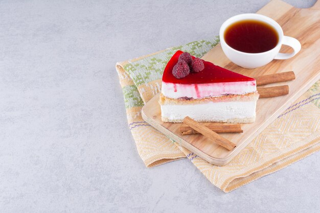 Tarta de queso y taza de té negro sobre tabla de madera.