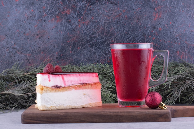 Tarta de queso y vaso de té sobre tabla de madera con decoraciones festivas. Foto de alta calidad