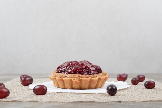 Tarta de tarta con frutas sobre arpillera y uvas. Foto de alta calidad