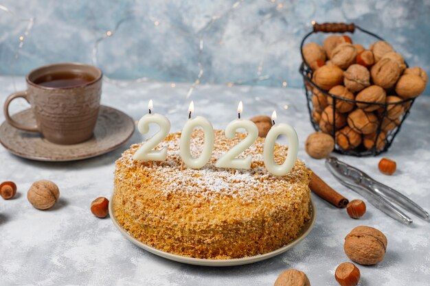 Tarta de zanahoria con velas 2020 y una taza de té sobre hormigón gris