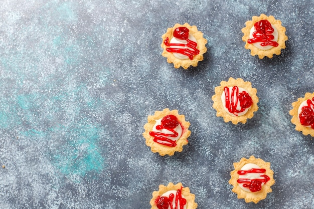 Foto gratuita tartaletas con relleno de chocolate blanco y mermelada de frutos rojos encima.