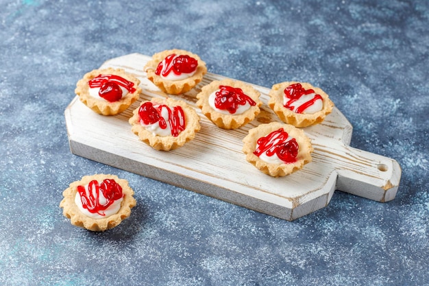 Tartaletas con relleno de chocolate blanco y mermelada de frutos rojos encima.