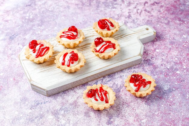 Tartaletas con relleno de chocolate blanco y mermelada de frutos rojos encima.