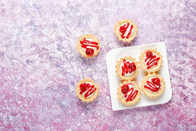 Foto gratuita tartaletas con relleno de chocolate blanco y mermelada de frutos rojos encima.