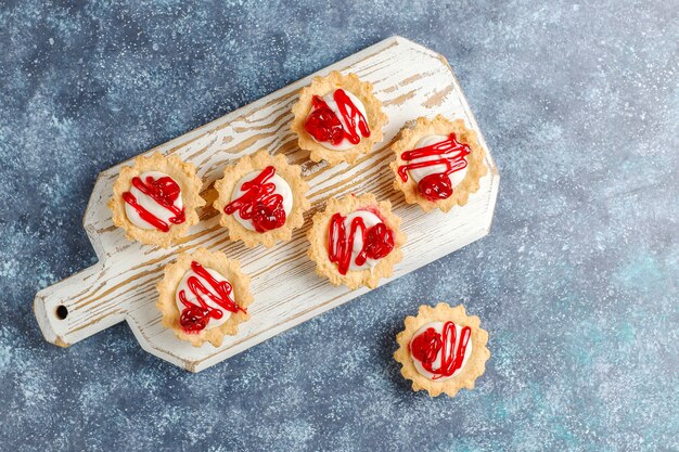 Tartaletas con relleno de chocolate blanco y mermelada de frutos rojos encima.