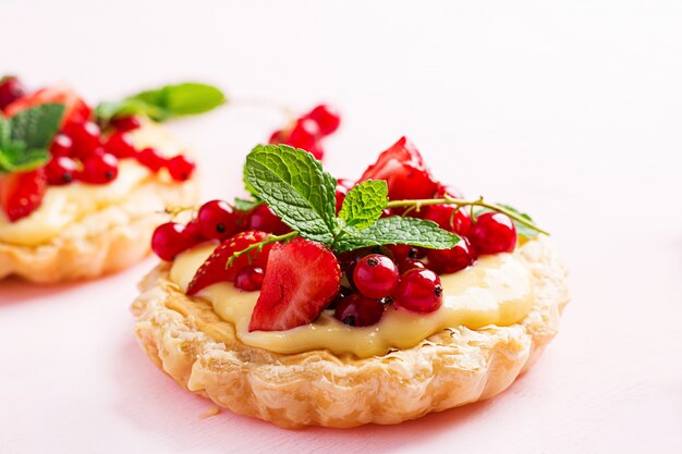 Tartas con fresas, grosellas y crema batida decoradas con hojas de menta