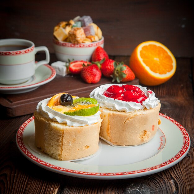 Tartas de frutas con fresa y naranja y una taza de té en un plato