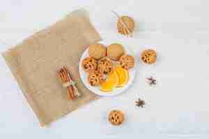 Foto gratuita tartas rellenas de gelatina, galletas y naranja en un plato con canela y un mantel individual