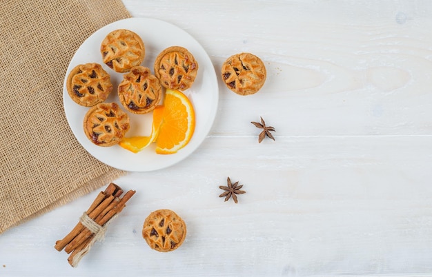 Foto gratuita tartas rellenas de gelatina y naranja en un plato con canela y un mantel individual