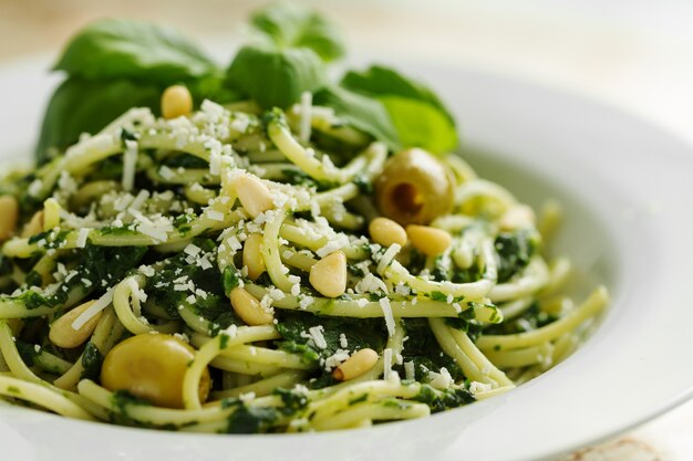 Tasty Pasta hermosa Closeup con espinacas, queso, aceitunas, albahaca y nueces.