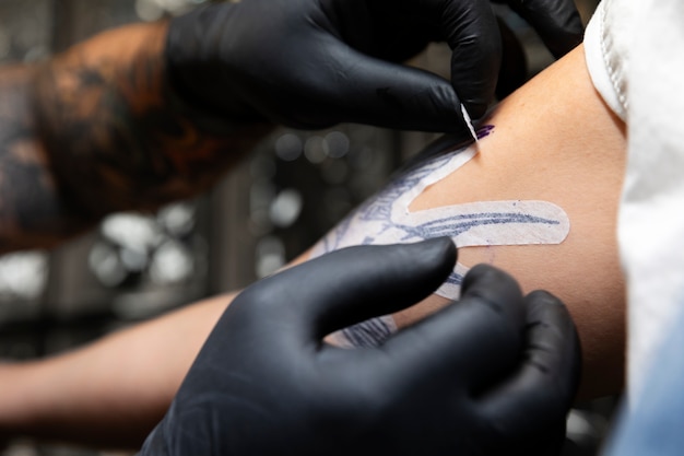 Tatuador experimentado que trabaja en el tatuaje del cliente.