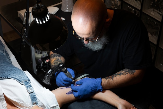 Tatuador experimentado que trabaja en el tatuaje del cliente.
