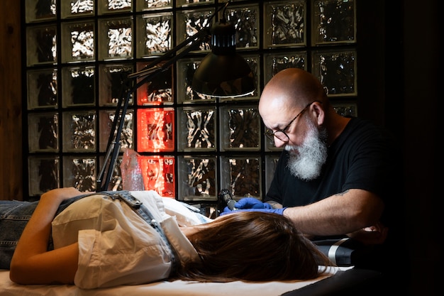 Tatuador experimentado que trabaja en el tatuaje del cliente.