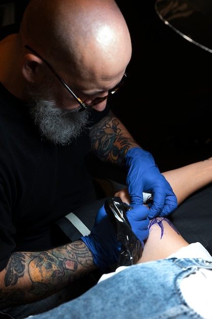 Tatuador experimentado que trabaja en el tatuaje del cliente.