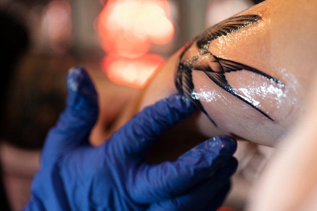 Tatuador experimentado que trabaja en el tatuaje del cliente.