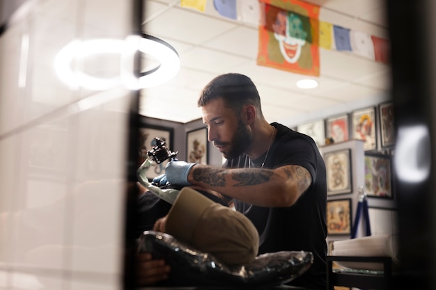 Tatuador haciendo su trabajo plano medio