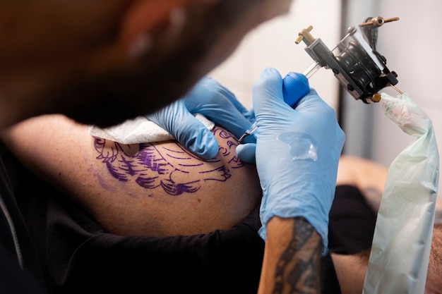 Tatuador talentoso de alto ángulo haciendo su trabajo