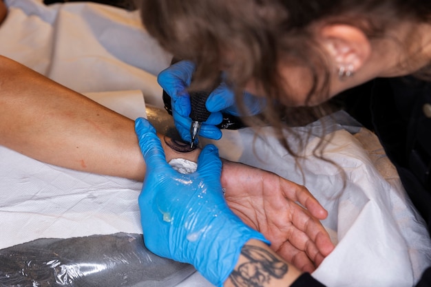 Tatuadora de alto ángulo haciendo su trabajo