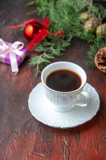 Una taza de accesorios de decoración de ramas de abeto de té negro y regalo sobre fondo oscuro