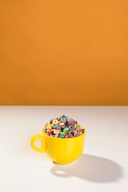 Taza amarilla de alto ángulo con cereales en la mesa