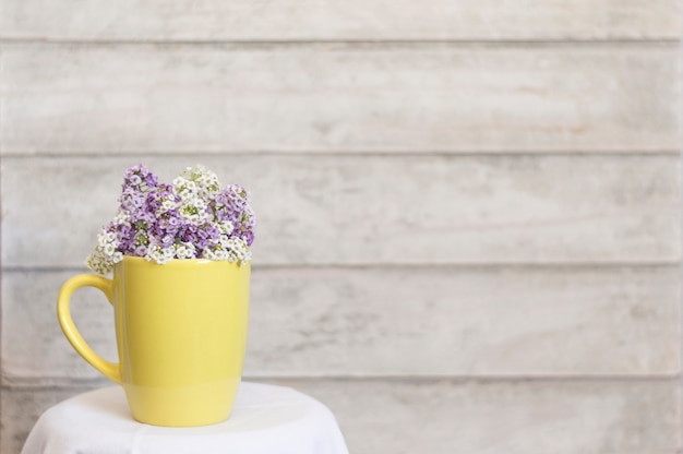 Taza amarilla elegante con flores y fondo de madera