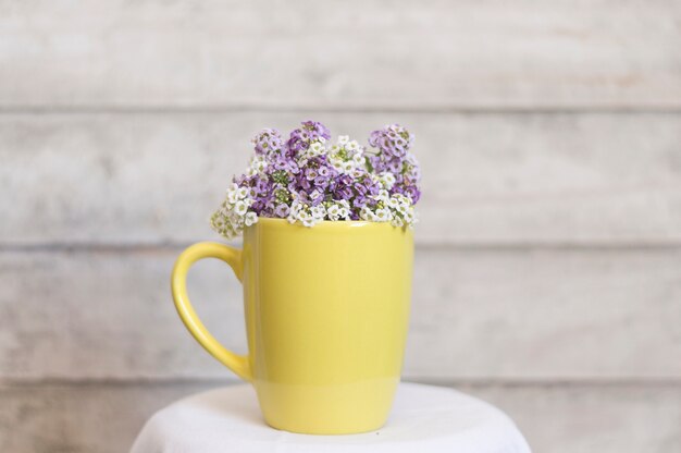 Taza amarilla con flores blancas y moradas