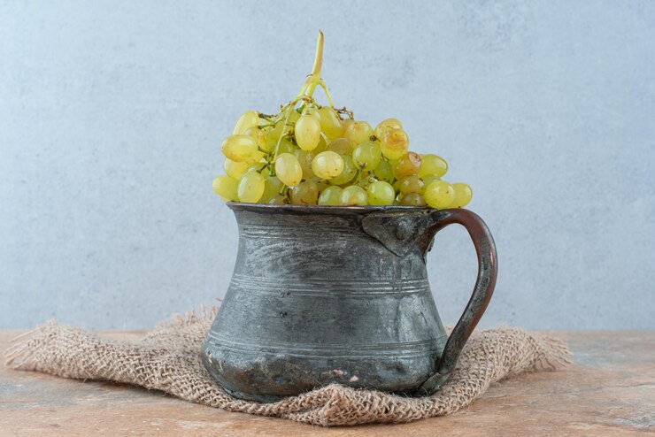 Foto gratuito una taza antigua llena de uvas dulces en mármol.