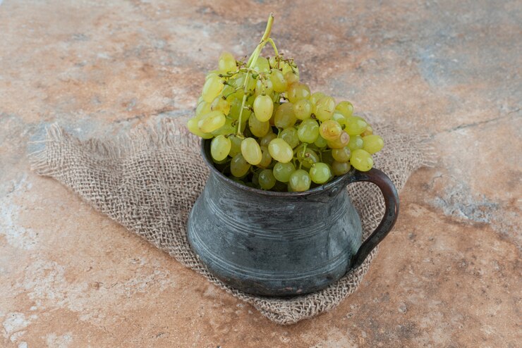 Foto gratuito una taza antigua llena de uvas dulces en la mesa de mármol.